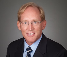 Attorney Jonathan O. Hafen looks professional in a suit and glasses while smiling at the camera