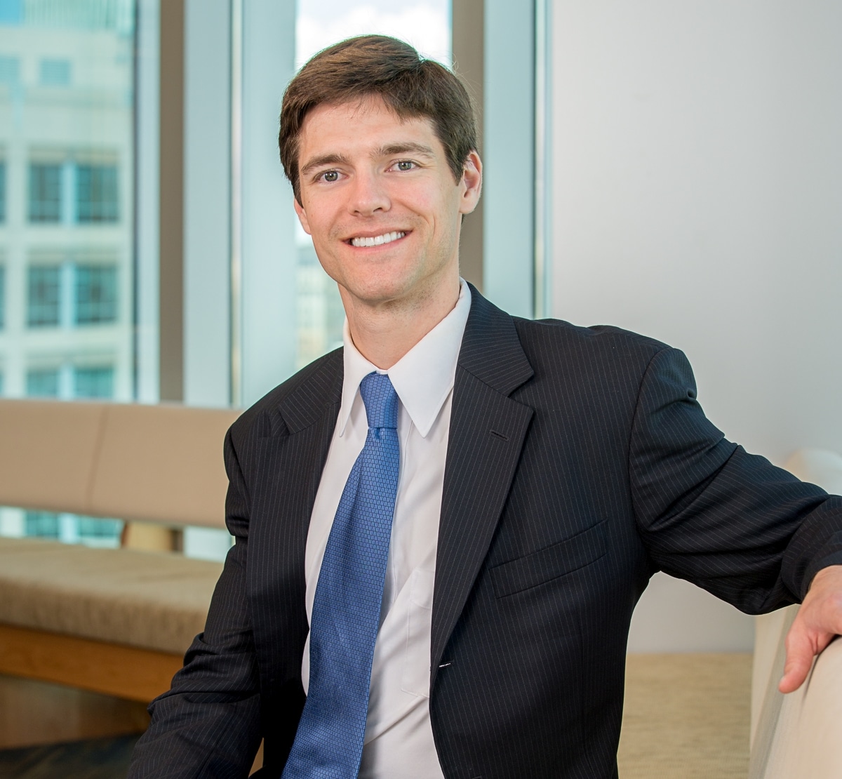 Austin J. Riter, an Attorney at Parr Brown Gee and Loveless, sits in an office and smiles at the camera