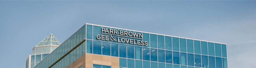 Exterior photo of Parr Brown Logo on upper side of glass building set against blue sky