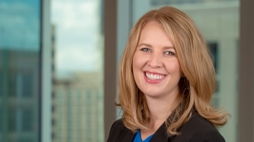 Attorney Jen Tomchak poses professionally and smiles in an office